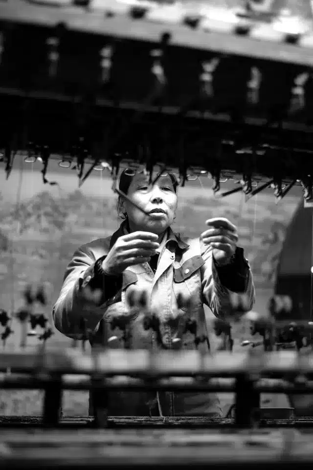 A pictured captured of a woman making silk in China using my DSLR camera for travel.